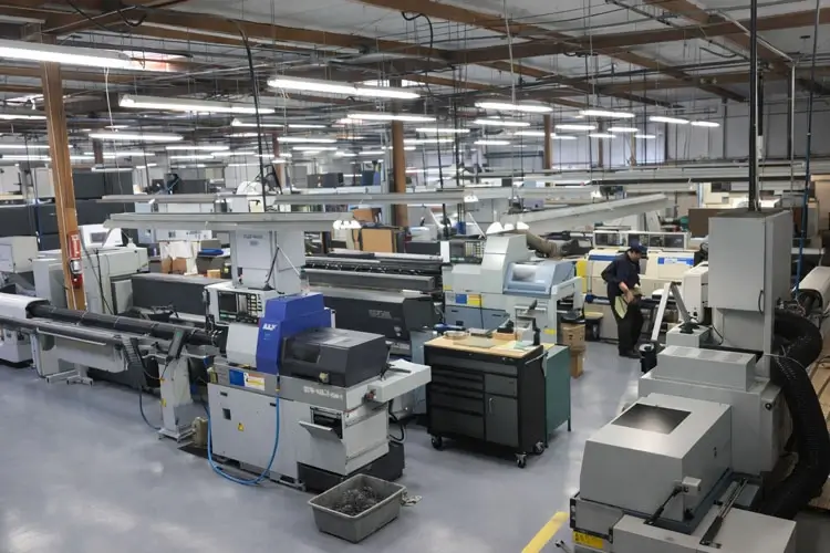 Wide view of our clean CNC machining facility floor showing automated turning centers and bar feeders in Oceanside, California.