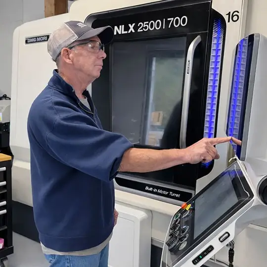 Machinist operating a DMG Mori NLX 2500 precision CNC turning center for Swiss machining components.